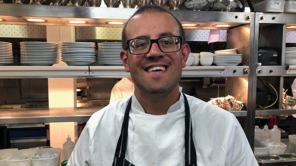 A man smiling in a restaurant kitchen