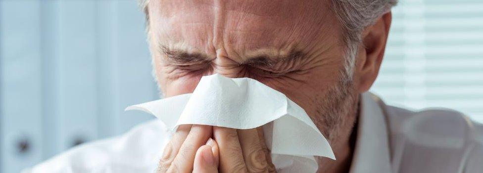 Man sneezing into handkerchief