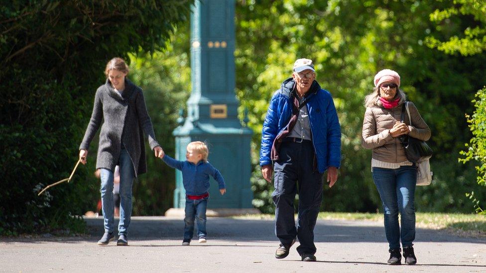 A woman and young child in the park near an older couple