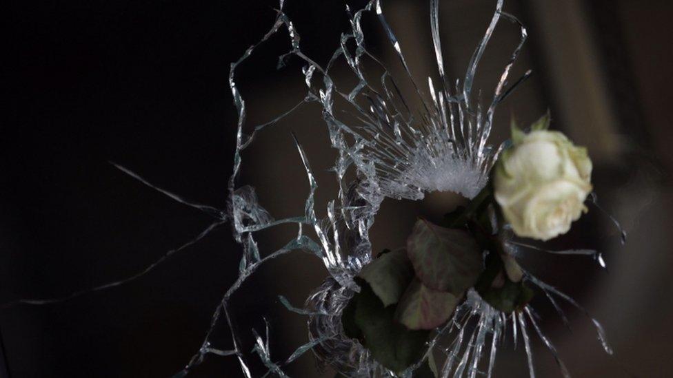 A rose in a bullet hole in the window of a restaurant in the city