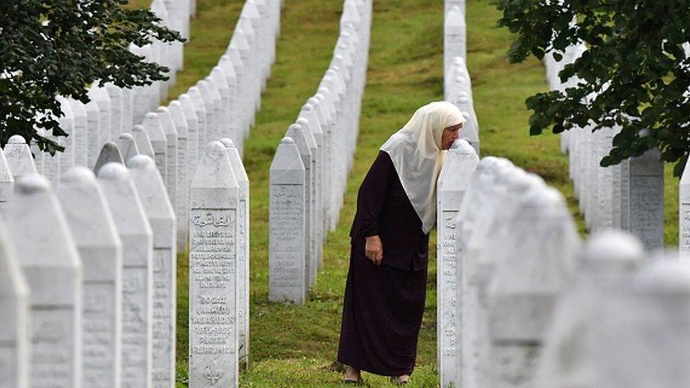 A survivor of Srebrenica 1995 massacre kisses her sons' tombstones