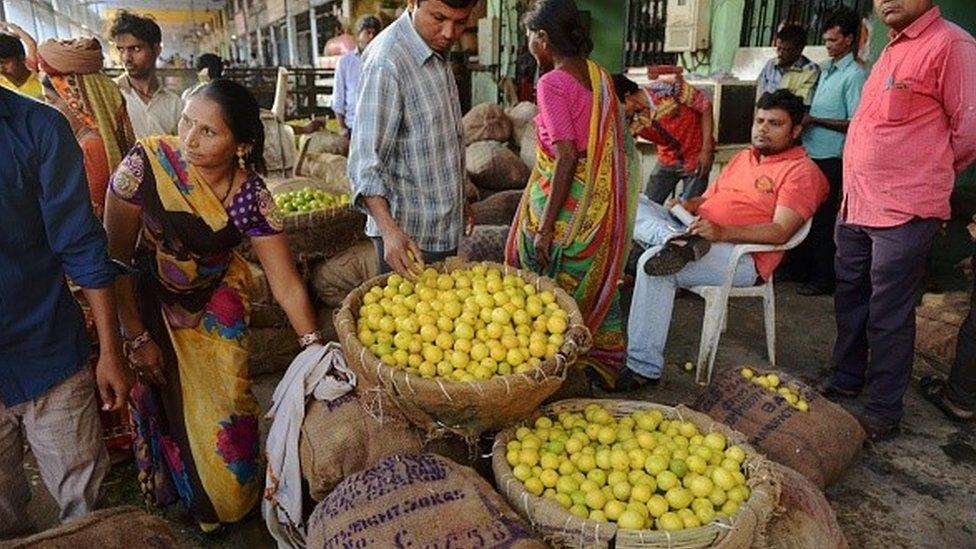 Indian customers check the quality of lemons for sale at a market in Ahmedabad