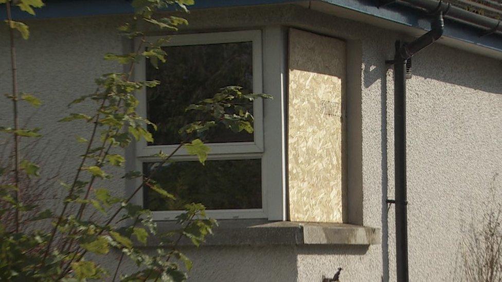 A boarded up window in a house following an arson attack