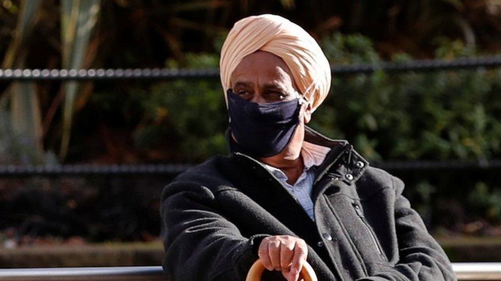 Elderly man sits on bench with walking stick