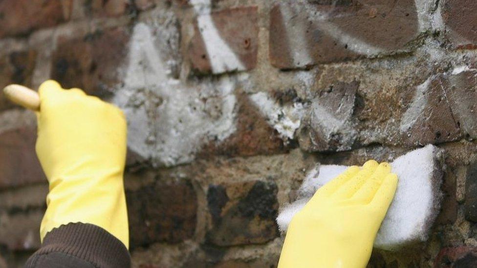 Youths cleaning a wall on a community payback scheme