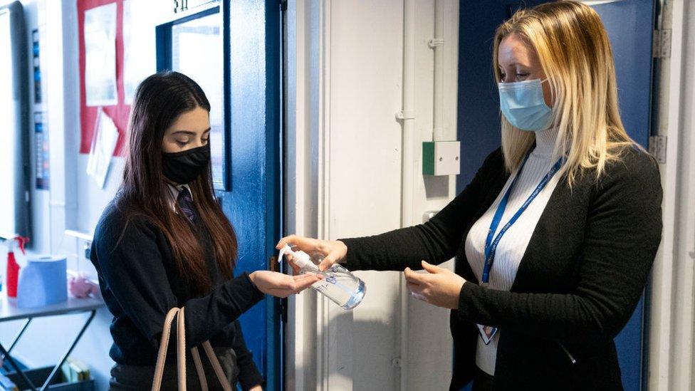 Teacher squirts hand sanitiser onto a pupil's hand