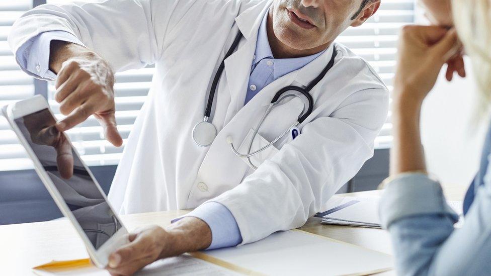 A doctor shows information to a patient on a tablet computer