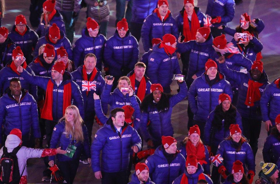 Team Great Britain athletes walk holding flags and recording on their phones