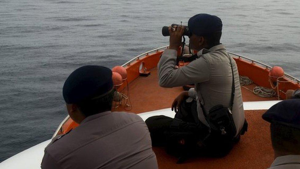 Rescue team members sit on top of a Basarnas boat as they take part in a search for passengers who were victims of a ferry sinking in the Gulf of Bone