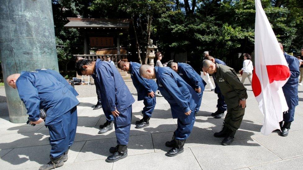 Members of a right-wing group bow their heads to honour the war dead at the shrine