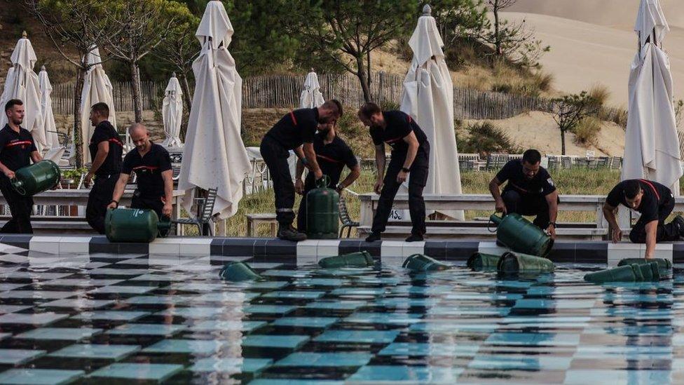 French firefighters fill canisters in a swimming pool