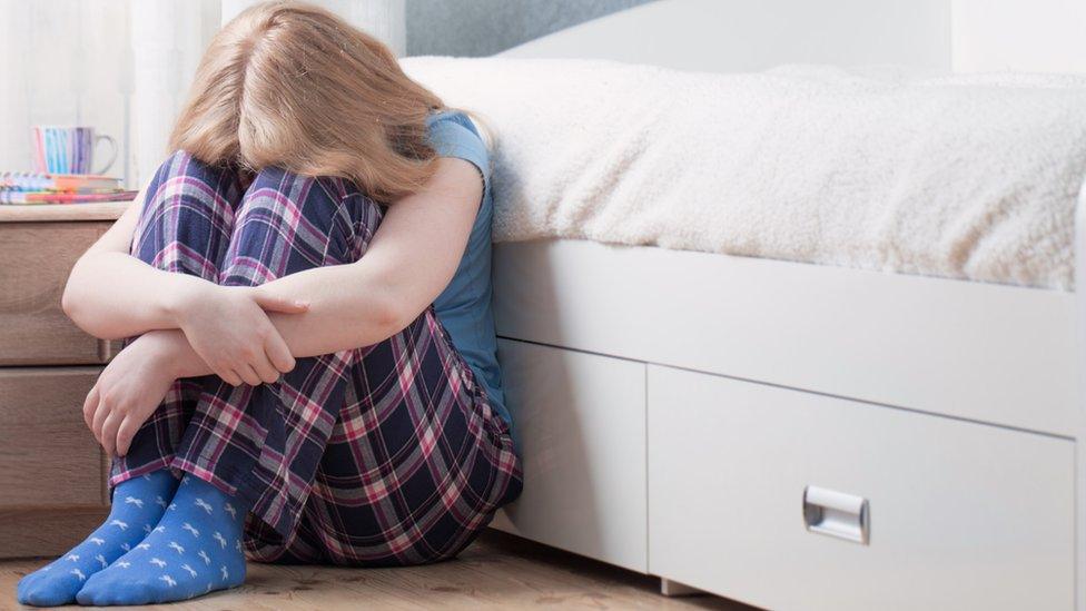 Girl sitting with head on her knees on the floor