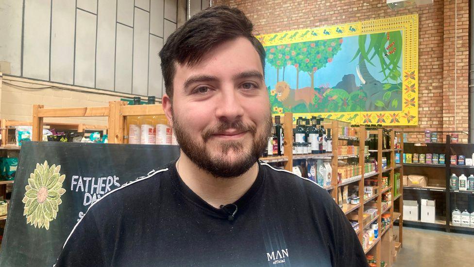 Cameron Sant in front of shelves of food