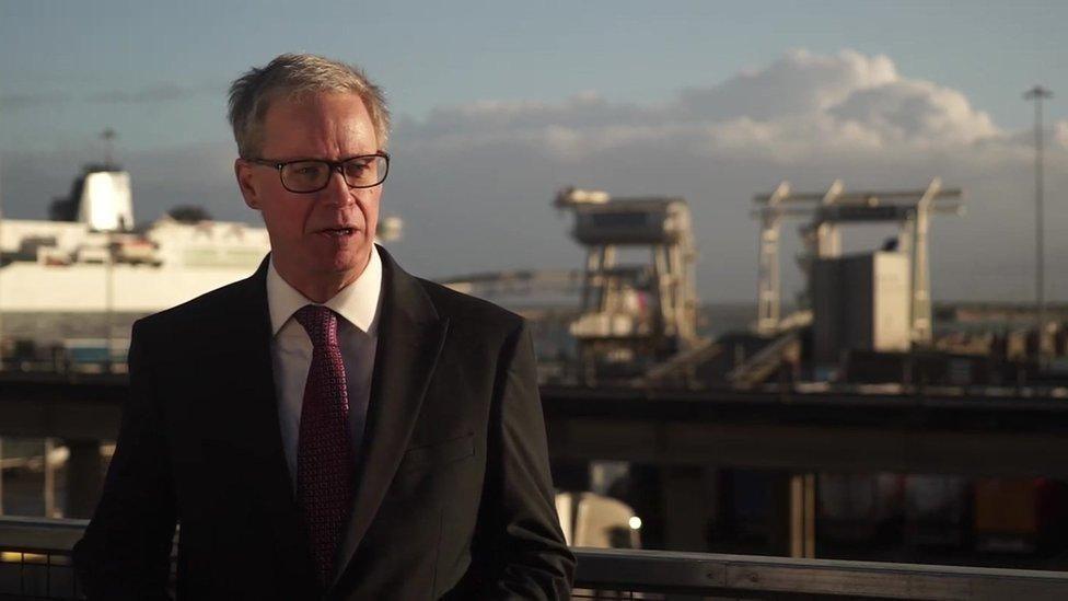 A man in a suit stood in front of a ferry port.