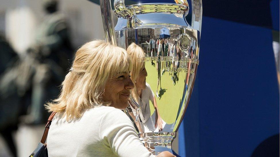 A woman poses with the Uefa Champions League trophy at the Plaza de Oriente square in Madrid