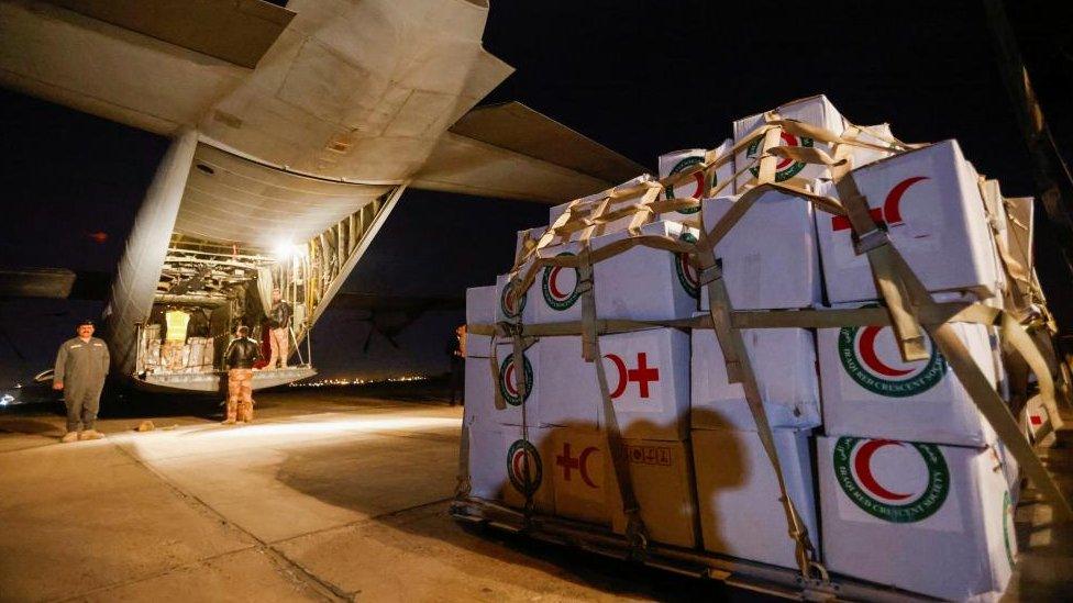 Red crescent aid in boxes near the entrance to a plane