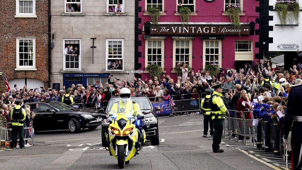 Crowds of people wave and cheer as King Charles and Camilla arrive in Hillsborough