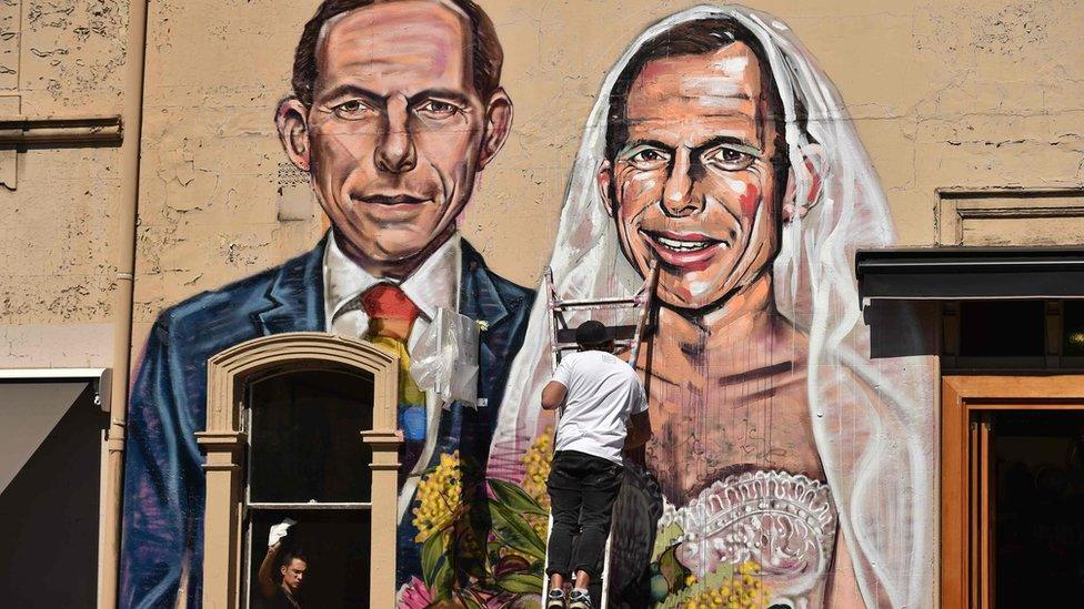 Australian street artist Scottie Marsh (C) painting a mural depicting former Australian prime minister Tony Abbott as the bride of Tony Abbott, in Sydney.