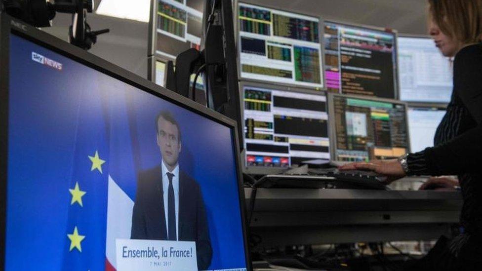 Screen showing Macron on a trading floor