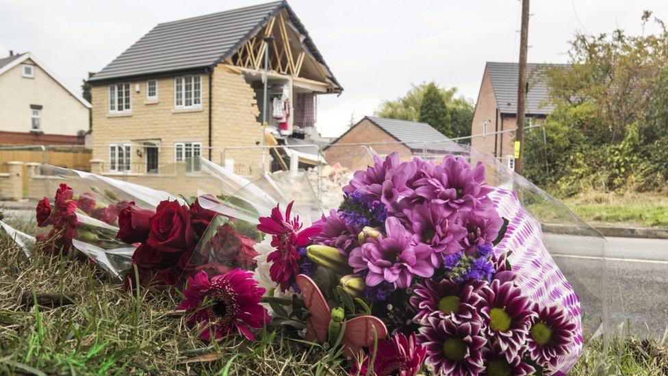 Flowers on the ground with damaged house in the background