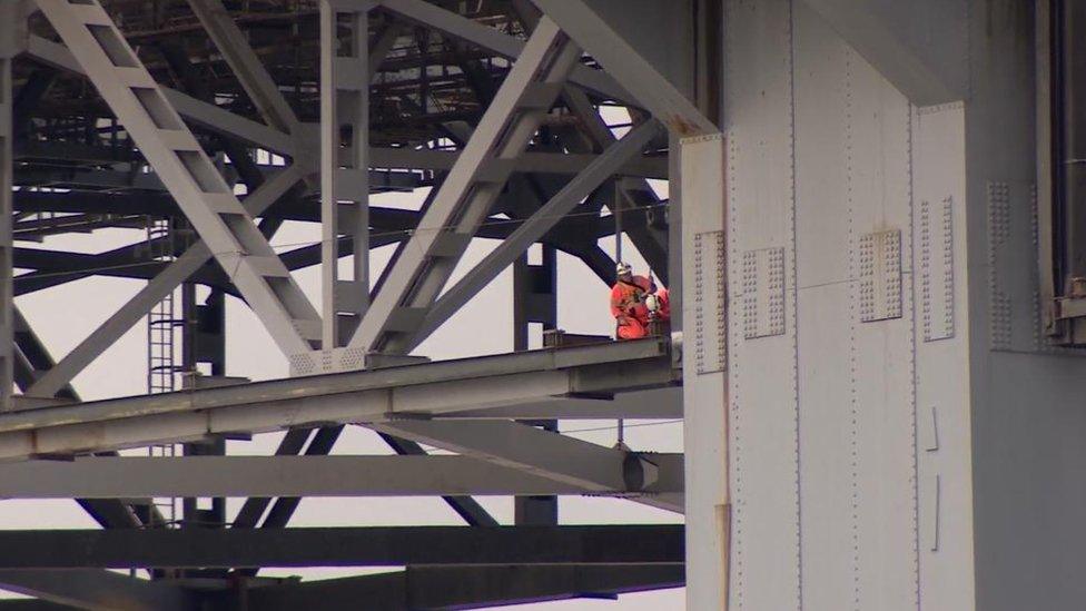 Man working on underside of bridge