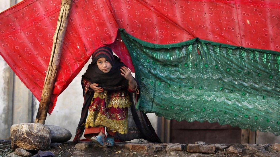 In this Sunday, Nov. 29, 2015 photo, an internally displaced girl peeks from a tent after her family left their village in Rodat district of Jalalabad east of Kabul