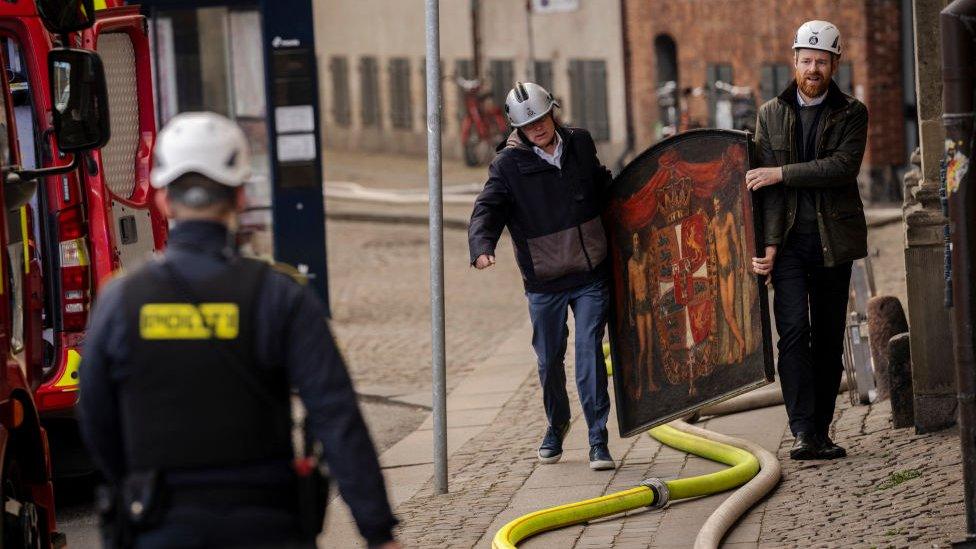 Mr Mikkelsen and a colleague carry an ornate historic painting