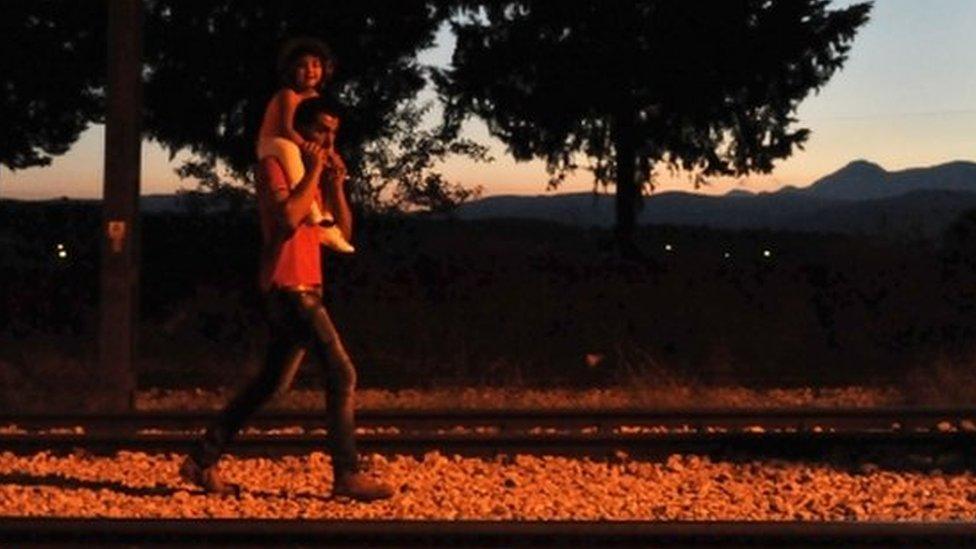 Migrants walk on the railway on the border between Greece and Macedonia near the town of Idomeni