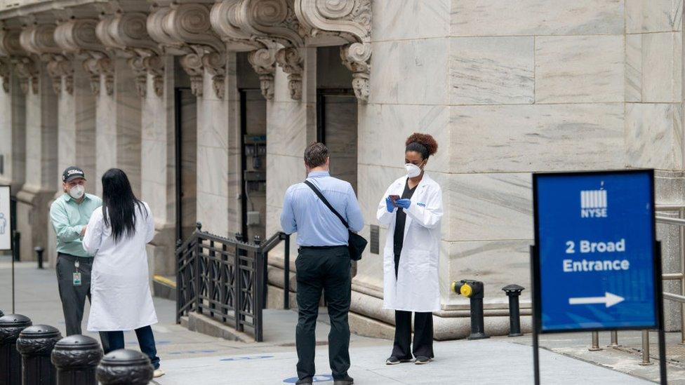 Employees screened by healthcare workers before entering the New York Stock Exchange, which partially reopened in late May