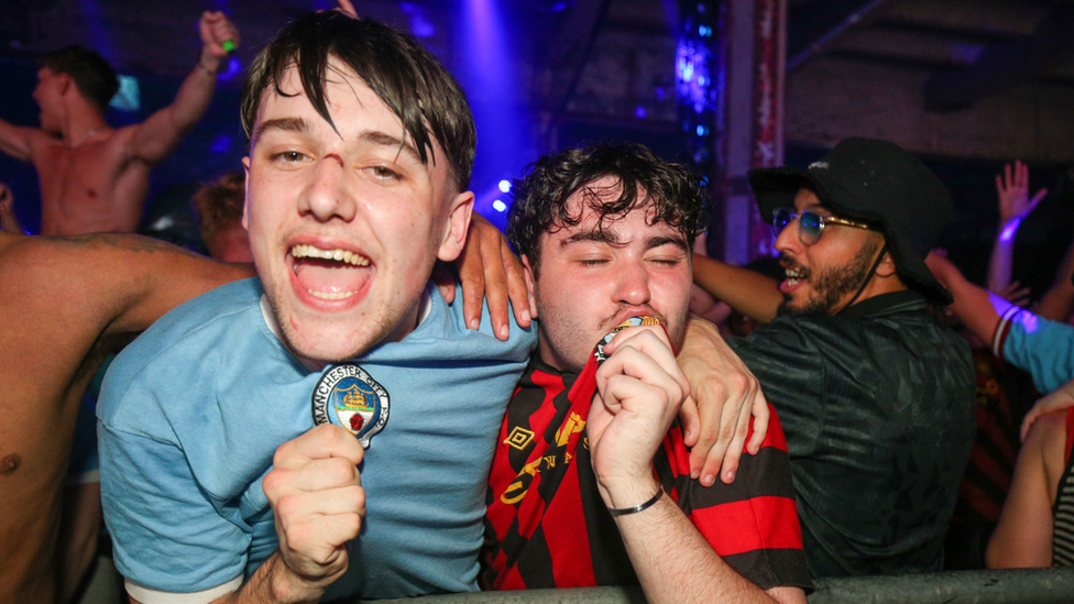 Two fans celebrating and one kisses the badge on his shirt