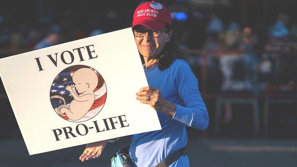 A woman holds a sign before Florida Governor Ron DeSantis speaks in Clearwater, Florida, on 5 November 2022