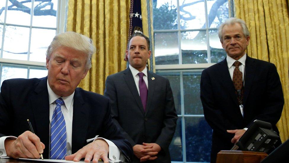 U.S. President Donald Trump, watched by (L-R) Vice President Mike Pence, White House Chief of Staff Reince Priebus, Head of the White House Trade Council Peter Navarro and senior advisor Jared Kushner, signs an executive order that places a hiring freeze on non-military federal workers in the Oval Office of the White House in Washington January 23, 2017