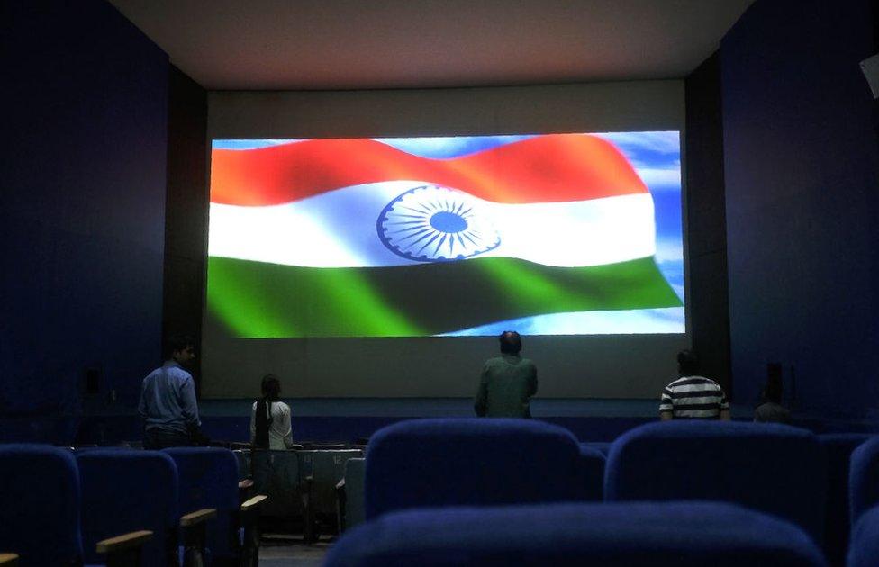 This picture taken on March 17, 2017 shows audience members standing for the Indian national anthem before a movie starts at the Regal cinema, an 84-year-old movie hall, in the heart of the Indian capital New Delhi