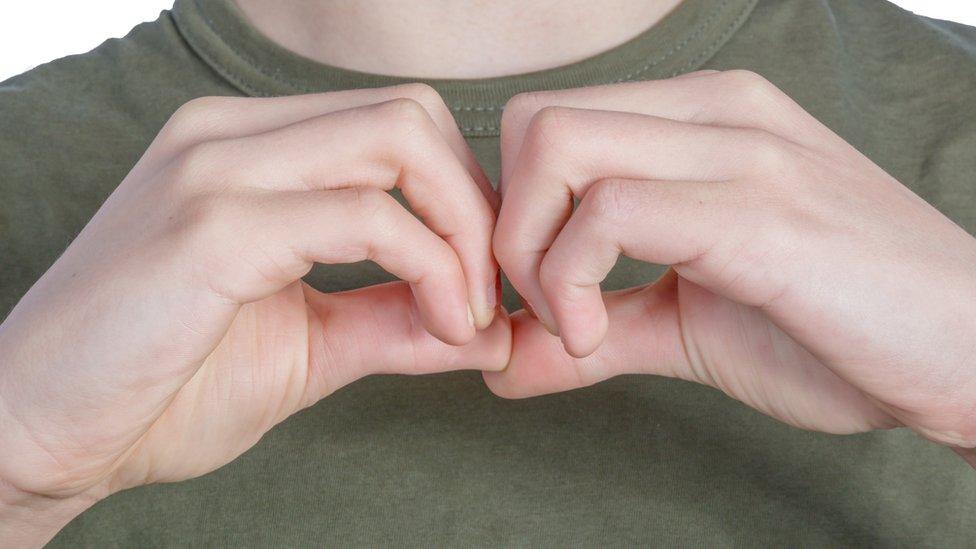 A person signing the British Sign Language symbol for a B