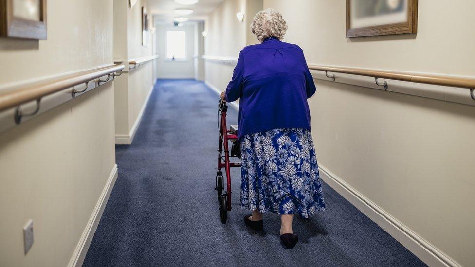 Elderly woman walking down a corridor