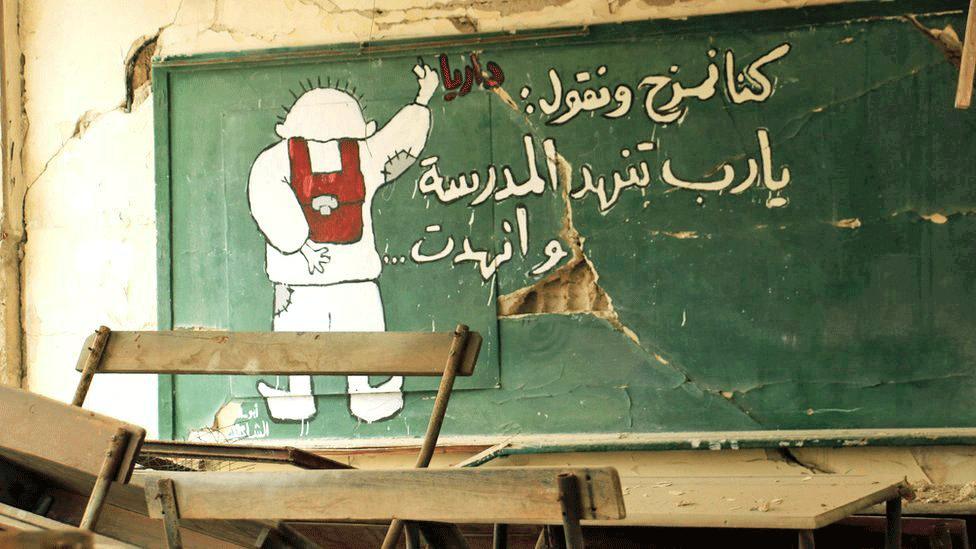 This mural was painted in a bombed-out school. The student is writing: 'We used to joke and say, God please destroy the school ... and he did.'