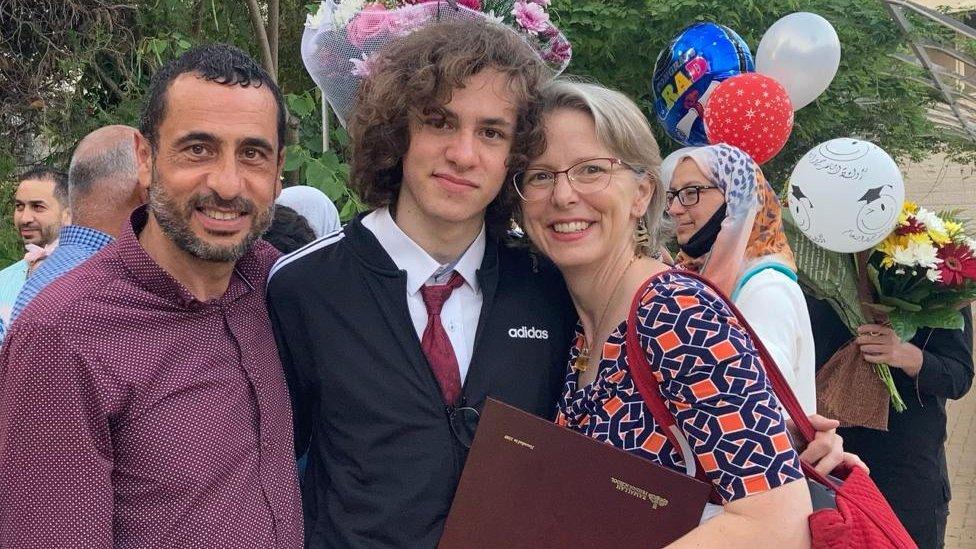 Hisham Awartani (middle) with his mother and father