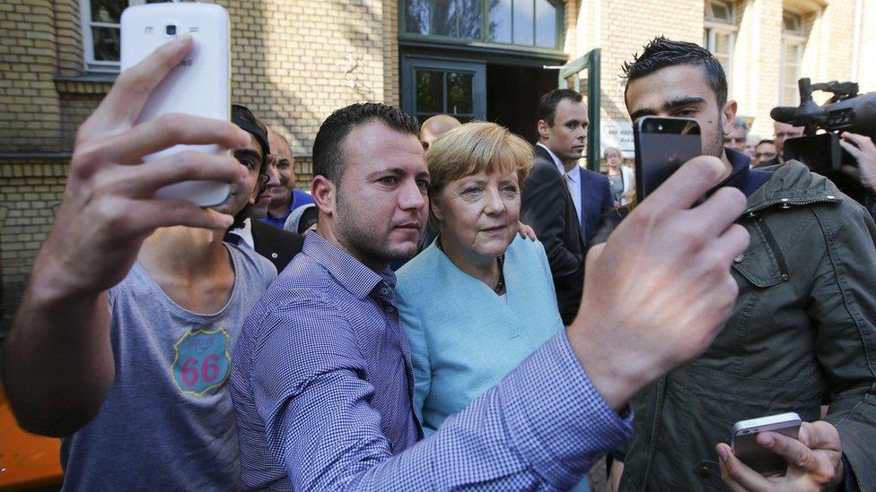 Migrants taking selfies with German Chancellor Merkel outside a refugee camp in Berlin