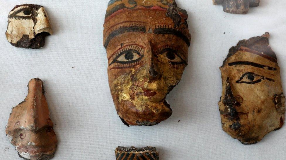 Painted segments of decorative faces on display at the tomb