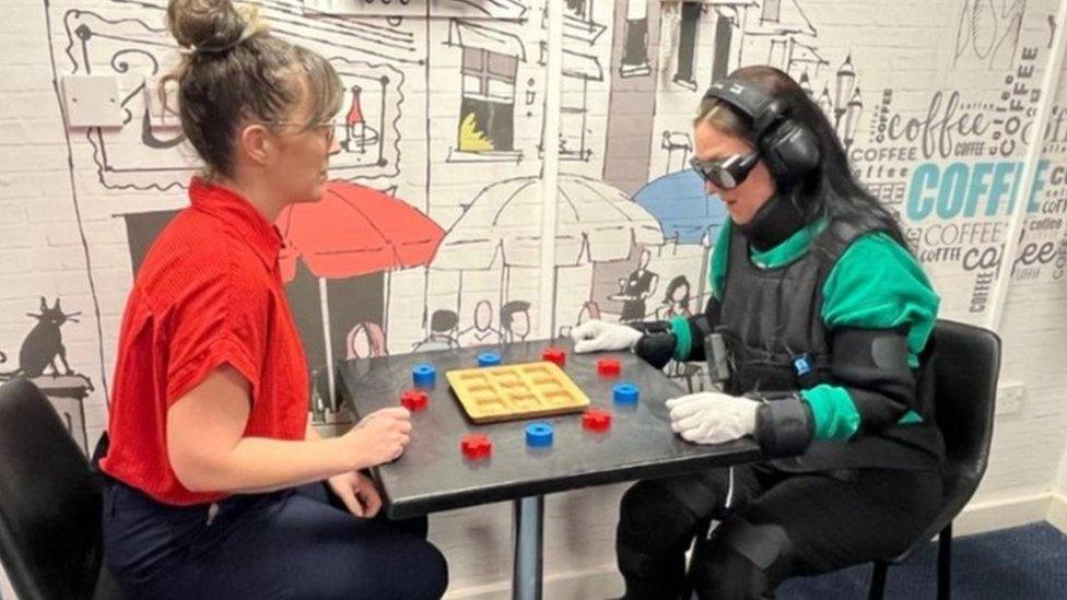 An employee playing a board game whilst wearing the suit