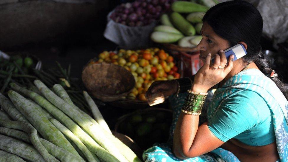 An Indian vendor uses her mobile phone to take customers orders at a wholesale market on the outskirts of Hyderabad on April 17, 2009.