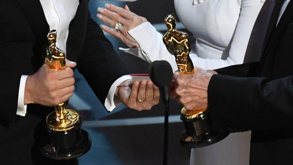 People holding Oscar statuettes