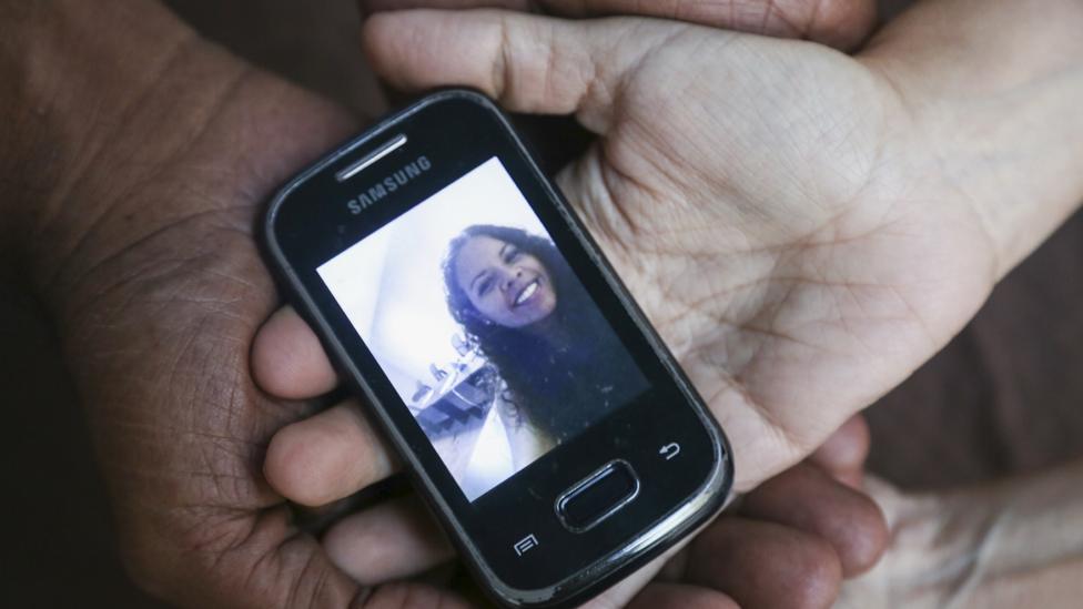 Dr María Alarcóm holds a phone with a photo of her daughter on it