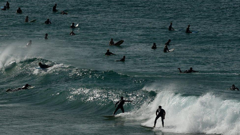 People surf at Bondi Beach following its reopening to the public in Sydney, Australia