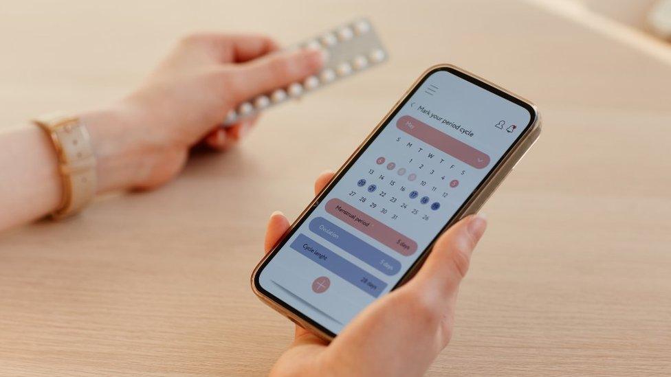 Woman holding her phone with a cycle tracking app open