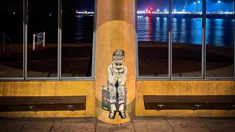 picture taken at night of the mural featuring the boy sat on his suitcase