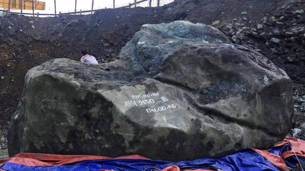 A man sits on giant jade stone at a mine in Phakant, Kachin State, northern Myanmar