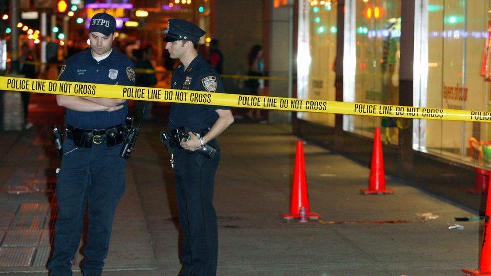 Two New York police officers standing behind crime scene tape