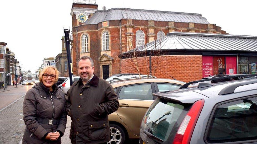 Theatre director Debbie Thompson and councillor James Bensly stand next to parked cars outside the theatre.