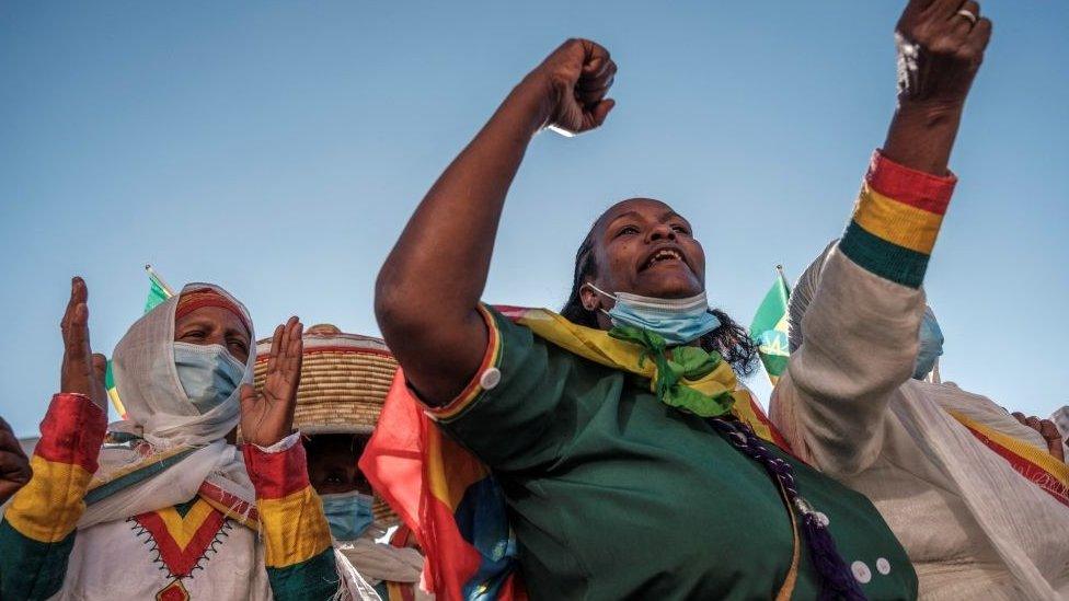 Women cheering and clapping, they are wearing the colours of the Ethiopian flag